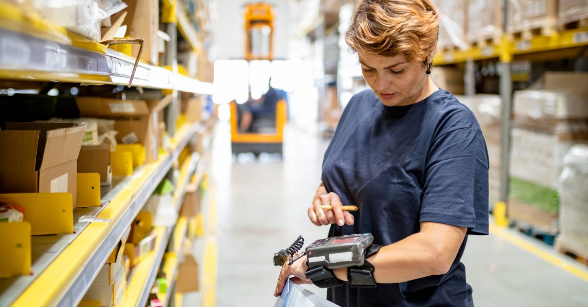 Woman in warehouse pushing buttons on wearable barcode reader